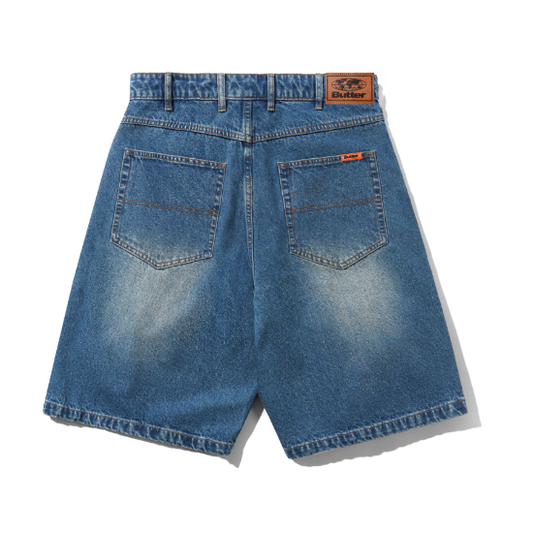 Back view of blue denim shorts with a faded wash, featuring two large patch pockets and a brown leather brand patch on the waistband.