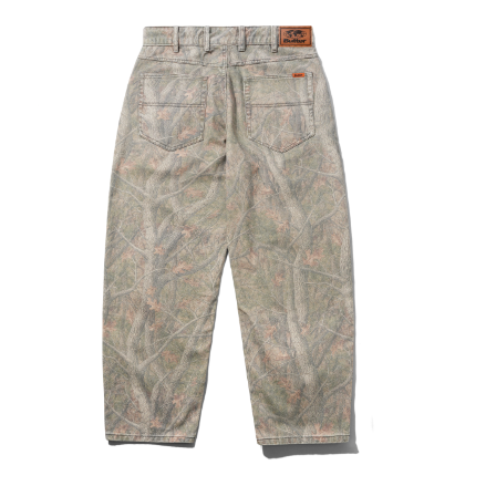Back view of camouflage pants with a woodland tree-bark pattern in muted green, brown, and beige tones, featuring a brown leather patch on the back waistband.
