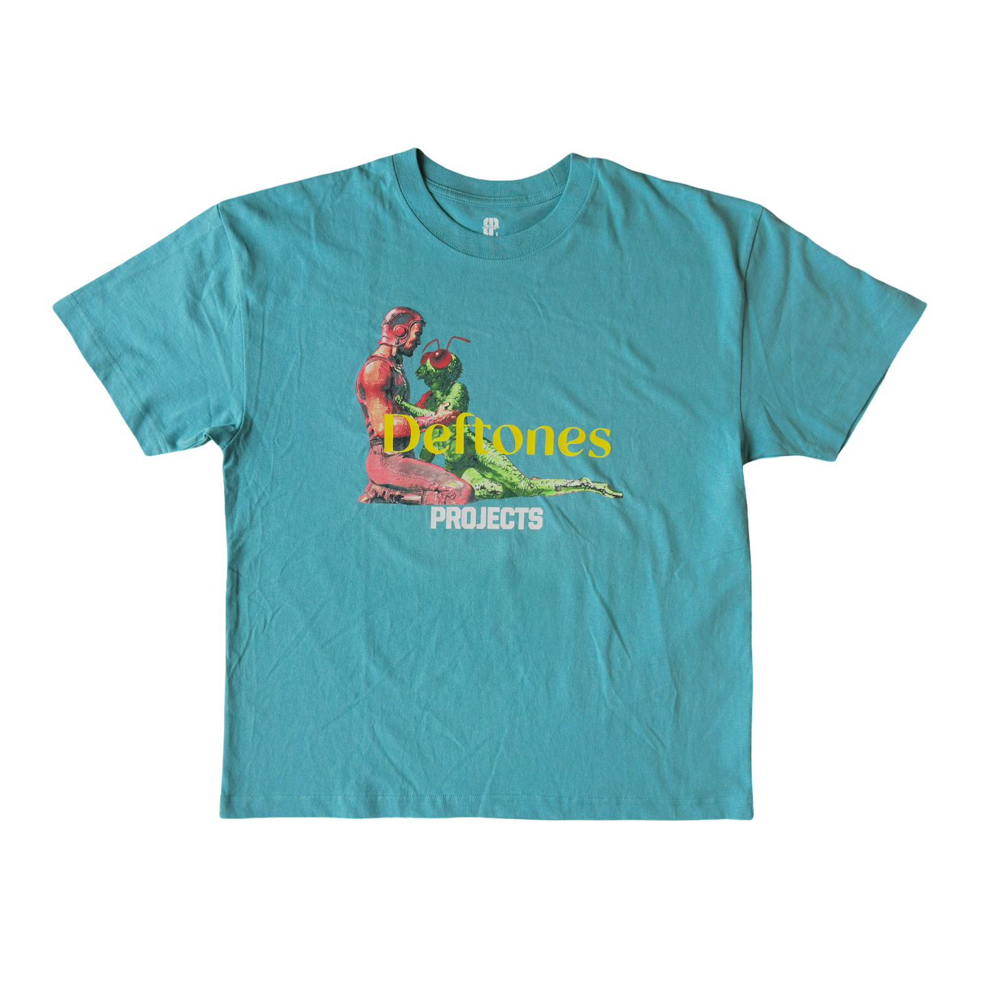 A turquoise blue crewneck t-shirt featuring a graphic print of a woman holding a green frog, with the text 'Deftones' in yellow and 'PROJECTS' in white below it, displayed on a solid white background.